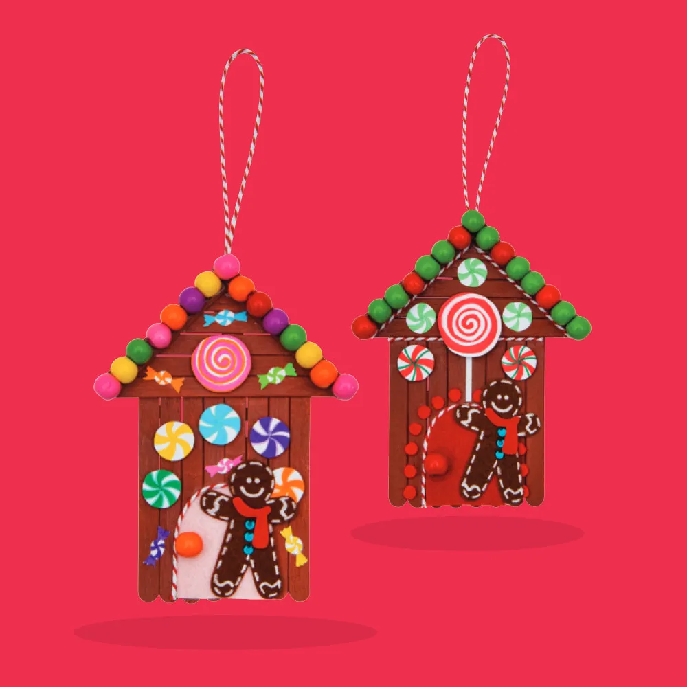 Colourful Christmas ornaments shaped like gingerbread houses made from red-painted craft sticks and decorated with mini pom-poms, lollies, and gingerbread characters.