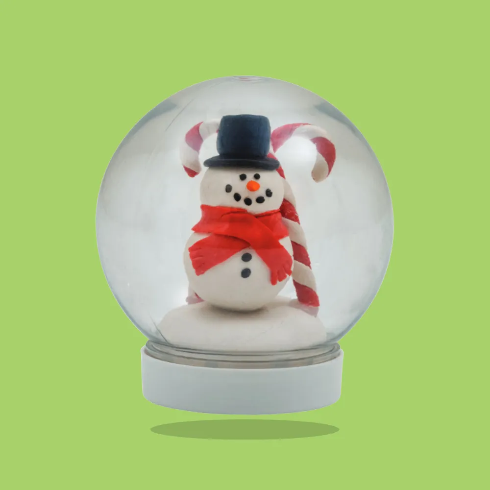 A small snow globe featuring a white snowman with a red scarf, black top hat, and two red-and-white candy canes, set against a green background.